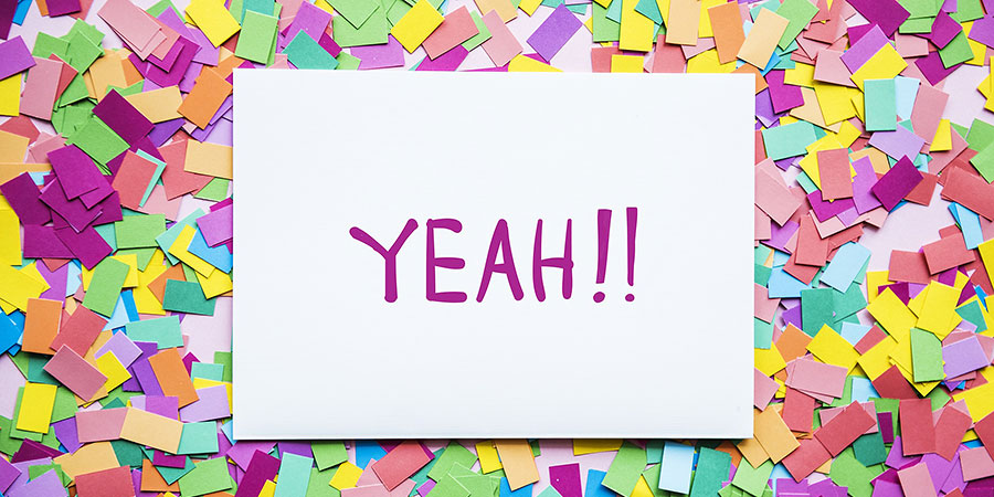 notecard with the word "Yeah!" lying on top of confetti
